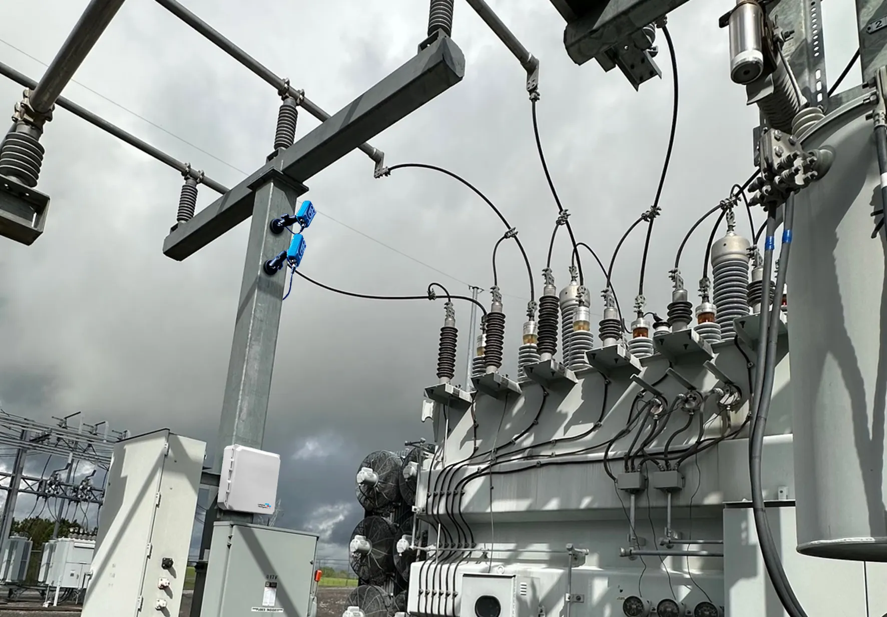 High-voltage transformer and insulators at a power substation under a cloudy sky